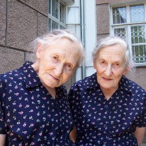 75-year-old identical twins wearing identical dresses.