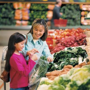 A mother and daughter shopping for vegetables at the supermarket.