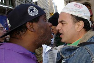 Two men stand almost nose-to-nose as they argue in the street.