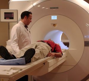 A doctor speaks to a patient who is lying on an fMRI before undergoing a scan.