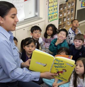 A teacher reads a story to a group of grade school students.