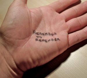 A note is written on a man's hand which says, "remember to remember."