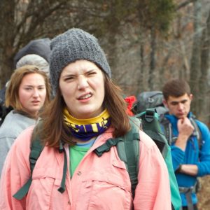 A group of hikers are stopped in the middle of a trail with confused looks on their faces.