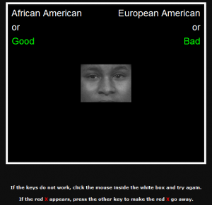 A screenshot shows a portion of the Implicit Associations Test. At the center a photo of a black man's face, from just above the eyebrows to just above the mouth, can be seen. At the top left corner the words 'African American or Good' appear. At the top right the words 'European American or Bad' appear. At the bottom of the screen the following instructions appear, 'If the keys do not work, click the mouse inside the white box and try again. If the red X appears, press the other key to make the red X go away.'