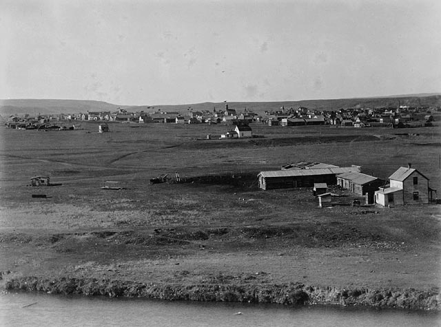 A black and white photo of a small town spread out over a flat plain.