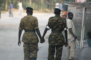 Two men in army uniforms walk down the street holding hands