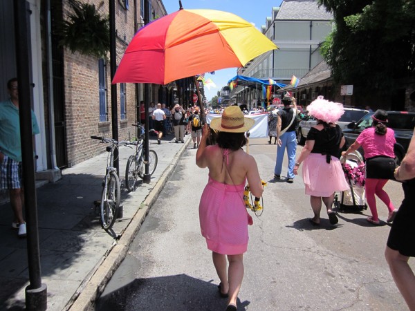 A woman carring a rainbow umbrella in a pride parade.