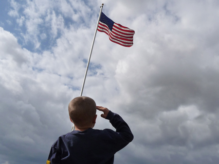 A young boy salutes the American flag.