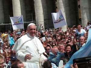 Pope Francis smiles at a surrounding crowd.