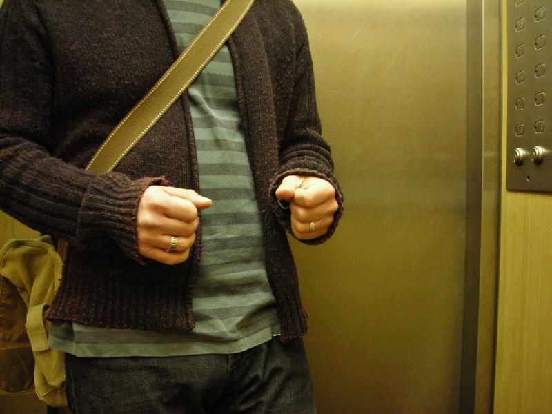 A man nervously clutches his fists inside an elevator.